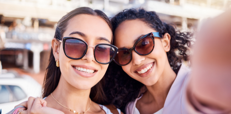 Two women taking a selfie wearing oversized, black sunglasses.