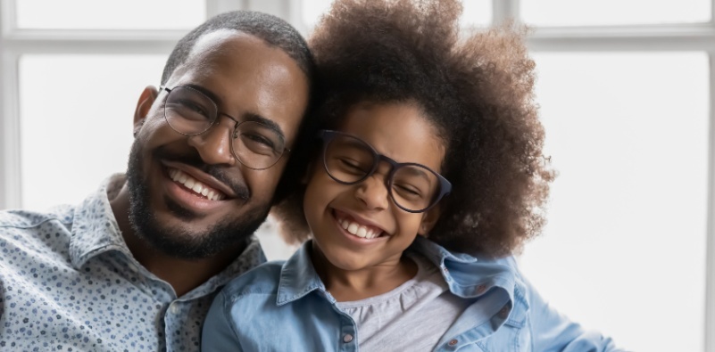 A man and his daughter, smiling, wearing glasses