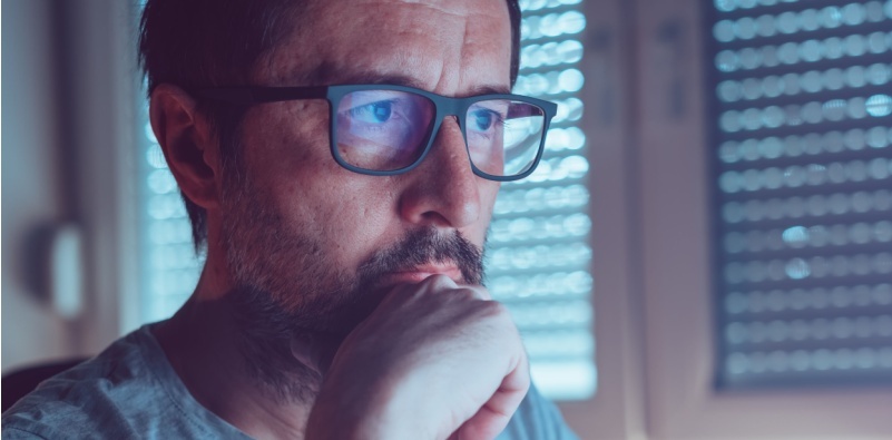 A man wearing blue light-blocking glasses while looking at a computer screen.