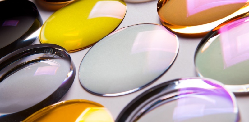 A selection of eyeglasses lenses of different thickness and lens coatings on a white surface