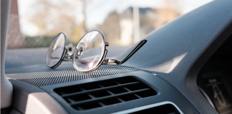 A pair of eyeglasses on the dashboard in a car