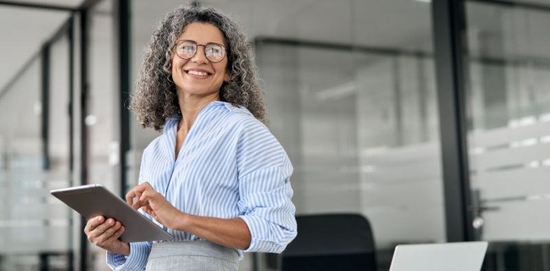 A working professional, in the office, wearing a pair of glasses and smiling