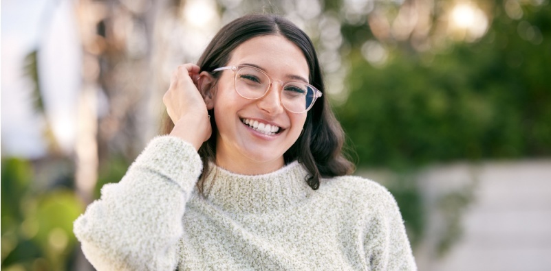 A woman wearing glasses, smiling outside