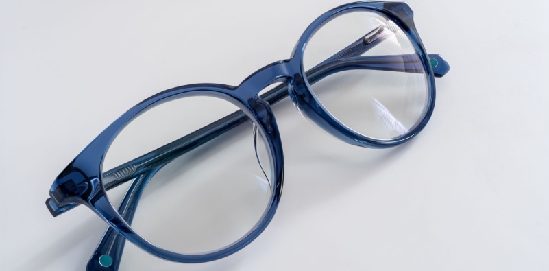 A pair of blue, prescription glasses on a white surface.