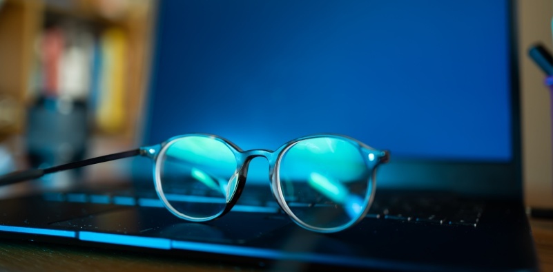 A pair of eyeglasses with blue light blocking lenses resting on a laptop keyboard, showcasing the perfect eyewear for digital device users.