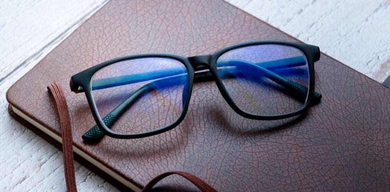 A pair of glasses with blue light blocking lenses resting on top of a notebook, perfect for professionals or students using screens frequently.
