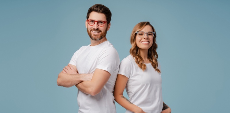 A man and a woman in white t-shirts wearing colorful glasses, smiling and showing off their stylish eyewear