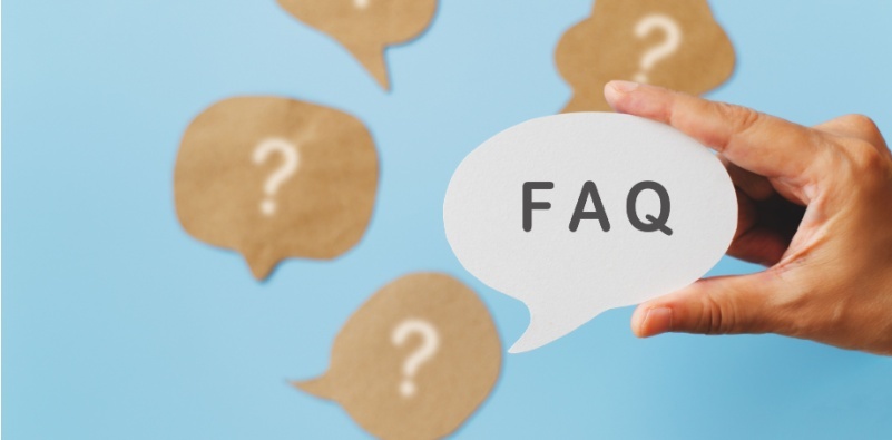 A hand holding a speech bubble with the text ‘FAQ’, surrounded by brown speech bubbles with question marks, symbolizing frequently asked questions about blue light glasses.