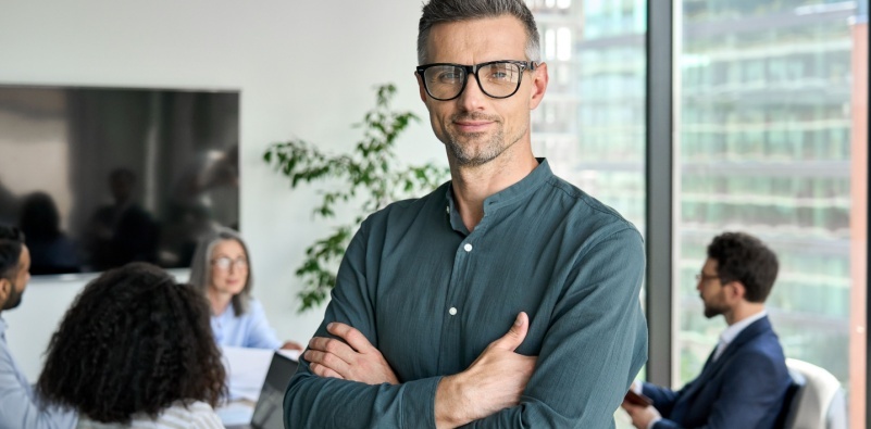 Smiling confident mature businessman leader wearing glasses posing for business portrait arms folded.