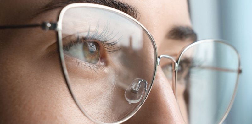 A closeup view of woman wearing eyeglasses on blurred background.