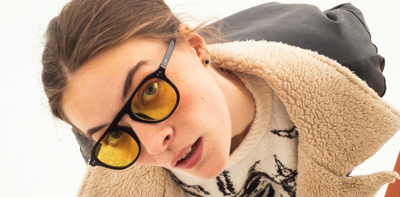 A stylish young woman wearing a pair of black eyeglasses with yellow lenses