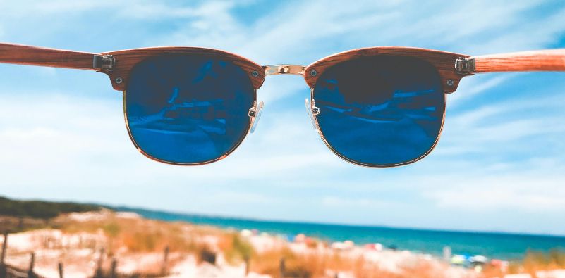 A point of view image looking through a pair of eyeglasses with blue lenses out towards the sea