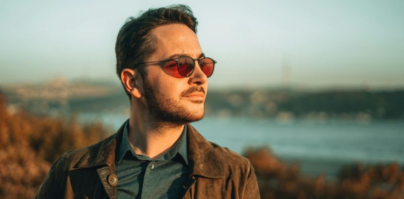 A stylish man stood outside, wearing eyeglasses with brown tinted lenses