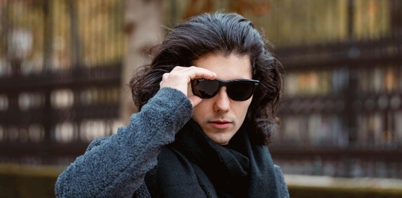 A man with dark hair wearing Ray-Ban Wayfarer sunglasses