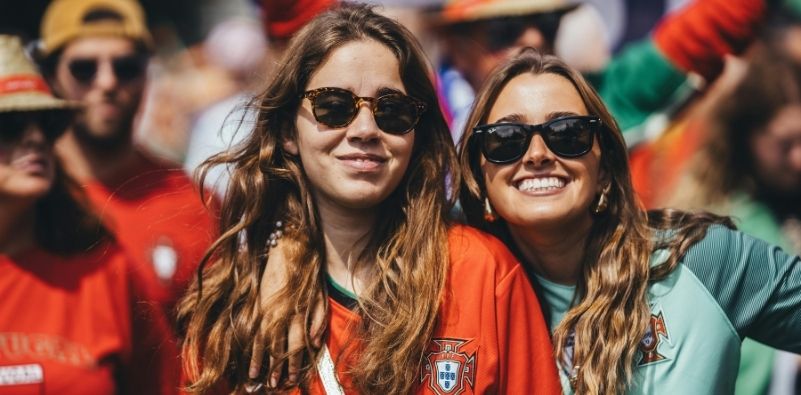 Two women smiling while wearing stylish sunglasses outdoors.